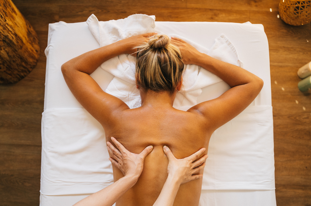 A Massage Therapist Putting Oil on a Client's Bare Back